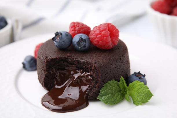 Delicious chocolate fondant, berries and mint on plate, closeup