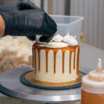 professional baker decorating a chocolate and cream cake with salty caramel